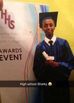 a man wearing a graduation cap and gown standing next to a sign that reads, awards event