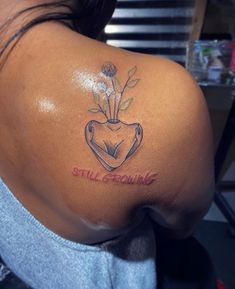 the back of a woman's shoulder with a tattoo on it that says still growing