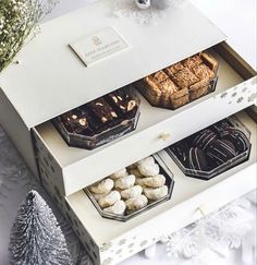 an open box filled with different types of desserts next to pine cones and snowflakes