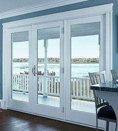 an empty dining room with french doors leading out to the water and decking area