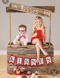 two children sitting on top of a wooden box with cupcakes in front of them