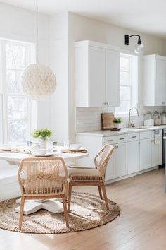 a dining room table and chairs in front of a large window with white cupboards