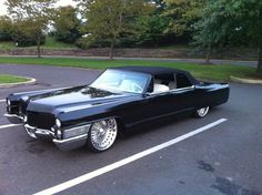 an old black car parked in a parking lot