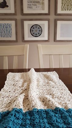 a crocheted blanket sitting on top of a wooden table next to two chairs