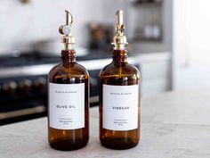 two brown bottles with white labels on them sitting on a counter top next to an oven