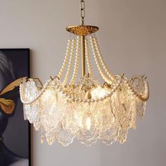 a chandelier with pearls hanging from it's center and two paintings on the wall behind it