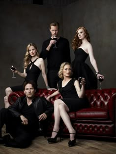 a group of people sitting on top of a couch with wine glasses in their hands