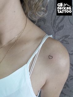 a woman with a small heart tattoo on her left shoulder and right arm behind her back