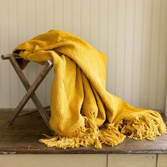 a yellow blanket sitting on top of a wooden table next to a chair and wall