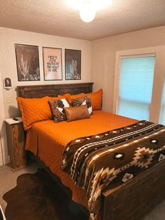 a bedroom with orange bedding and pictures on the wall over the bed, along with two nightstands