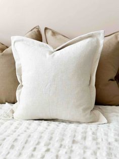 a white bed topped with lots of pillows