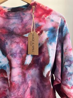 a pink and blue tie dye shirt with a tag on the front that says peace is still