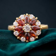 a red and white diamond ring sitting on top of a green cloth