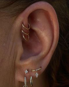 a woman's ear with three different types of piercings