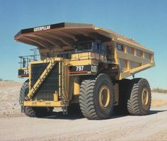 a large yellow dump truck parked on top of a dirt field