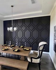 a dining room table with two chairs and a bench in front of a black wall