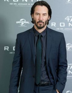 a man in a suit and tie posing for the camera at a red carpet event