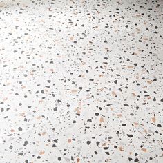 a white floor with black, orange and grey speckles on the top half