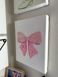 two pictures are hanging on the wall next to each other, one with a pink bow