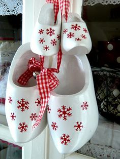 white shoes with red snowflakes hang from a hook on a window sill