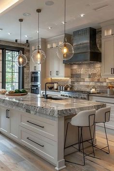 a large kitchen with marble counter tops and white cabinets, along with two bar stools