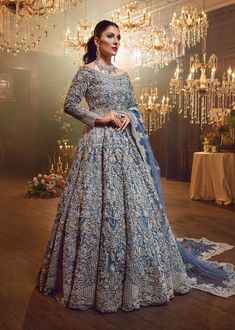 a woman in a blue gown standing next to a chandelier