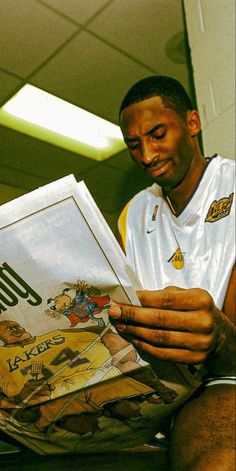 a man sitting on the floor reading a book with an ad in front of him