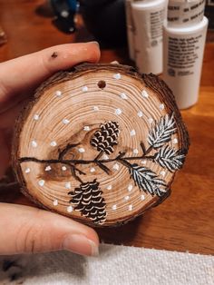 a person holding a piece of wood with pine cones and snowflakes on it