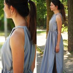 a woman wearing a gray dress standing in front of trees