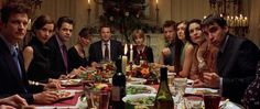 a group of people sitting around a dinner table with food and drinks in front of them