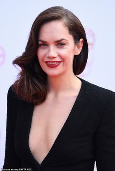 a woman in a black dress smiling at the camera