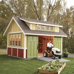 a man on a lawn mower in front of a shed with an attached garage