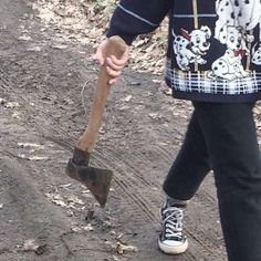 a person walking down a dirt road with a shovel