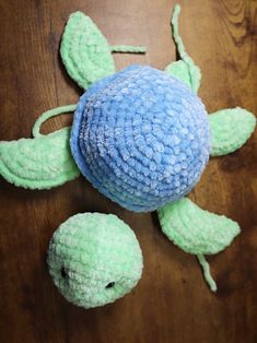 a blue and green stuffed animal laying on top of a wooden table