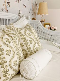 a white bed topped with pillows next to a night stand and lamp on top of a table