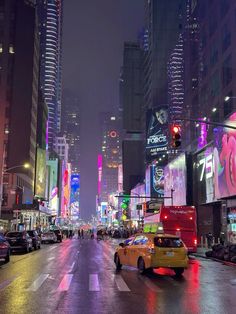 a busy city street at night with cars and people walking on the side walk in front of tall buildings