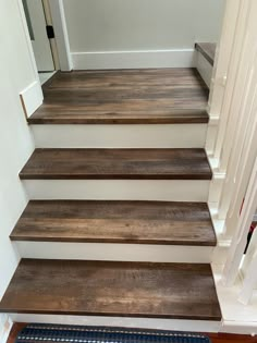 some wooden stairs in a house with white walls and blue rugs on the floor