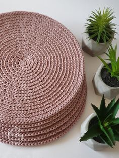 a pink round rug next to two potted plants