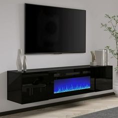 an entertainment center with a large television mounted on it's wall and a blue flame in the middle