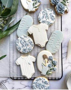 cookies decorated with blue and white frosting on a cooling rack next to some flowers