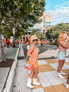 two women standing on the side walk with their hands in each other's pockets