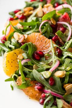 a salad with oranges, spinach and nuts on a white plate