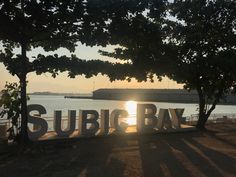 there is a sign that says subic bay in front of some trees and water