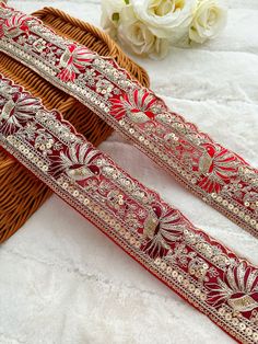 two red and gold ribbons sitting on top of a white blanket next to a wicker basket