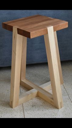 a small wooden stool sitting on top of a tile floor next to a blue couch