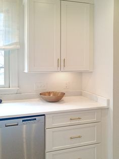 a white kitchen with a dishwasher, sink and window in the back ground