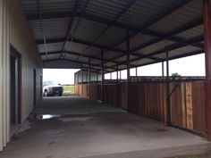 an empty building with a truck parked in the back ground and wooden fence around it