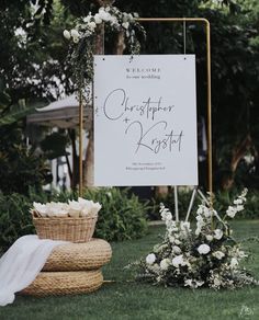 a sign that is sitting in the grass near some baskets and flowers on the ground