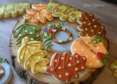 decorated cookies are sitting on top of a tree stump with leaves and dots around them