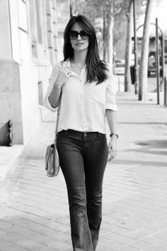 a woman walking down the street with her hand in her pocket and holding a purse